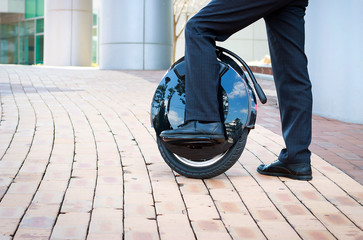 office worker is driving on an electric mono wheel, side view - obrazy, fototapety, plakaty
