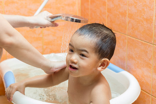 Closeup 2 year old Child bathing in bathtub with his mom
