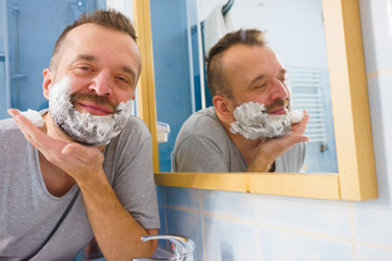 Guy shaving his beard in bathroom
