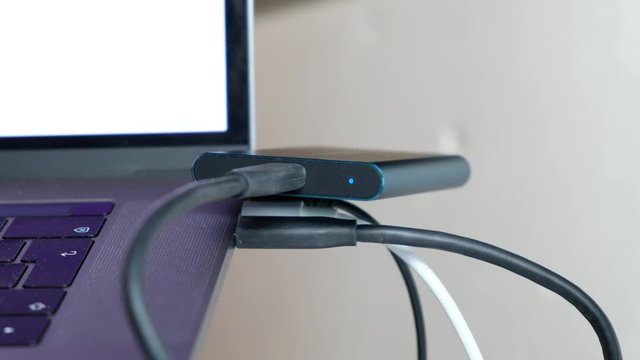 Footage of Guy connecting black usb-c cable t5 ssd to macbook pro with Touch Bar.