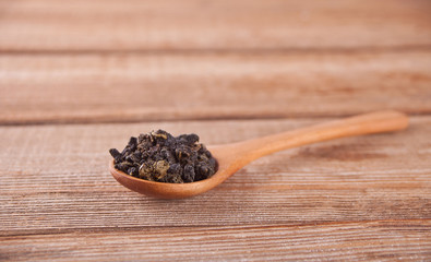 Black dry tea leaves with wooden spoon on the wooden table