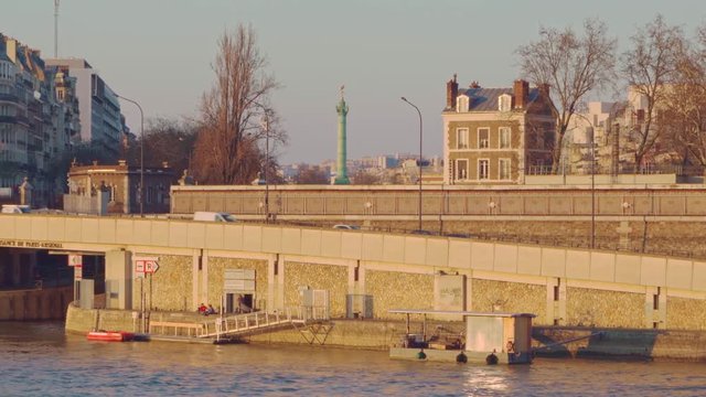 A close up of the riverside of the river Seine and the Jupiter Column at la Place de Bastille at sunset in Paris, France