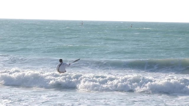 Canoeist tries to get over huge waves on a beach in dubai.