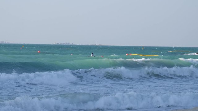 A canoeist swims on the shore of dubai with his conoe and tries to get over the waves.