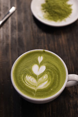A cup of green tea matcha latte on wooden background