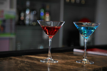 Image of two martini glasses filled with cocktails standing on the bar counter.