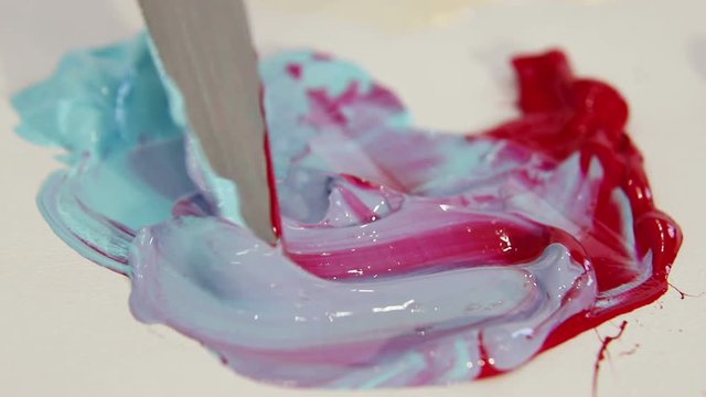 Painter spatula for drawing, mixes blue and red color close-up