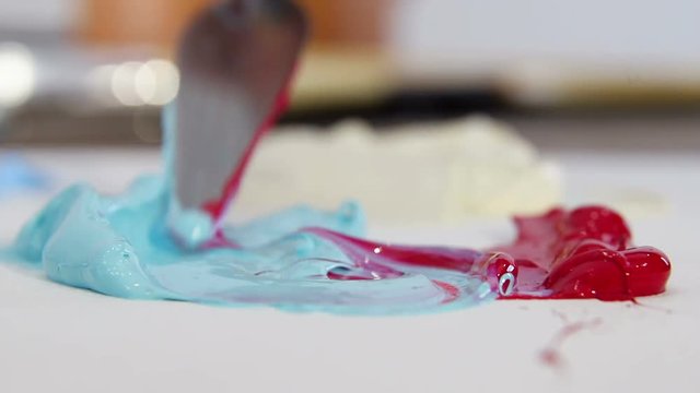 Painter spatula for drawing, mixes blue and red color close-up