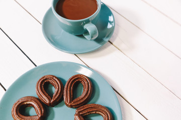 spanish chocolate fritters served on a blue dish on a wooden table with a cup of hot chocolate