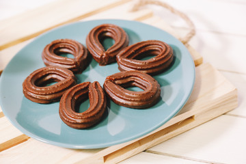 spanish chocolate fritters served on a blue dish on a wooden table with a cup of hot chocolate