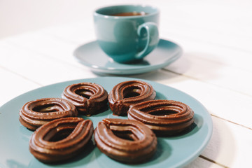 spanish chocolate fritters served on a blue dish on a wooden table with a cup of hot chocolate