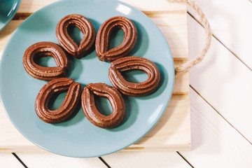 spanish chocolate fritters served on a blue dish on a wooden table with a cup of hot chocolate