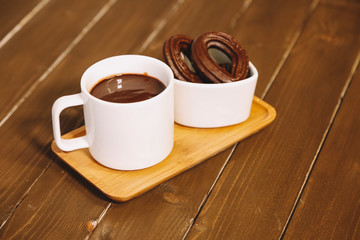 small spanish chocolate fritters served on a wooden table with a cup of hot chocolate
