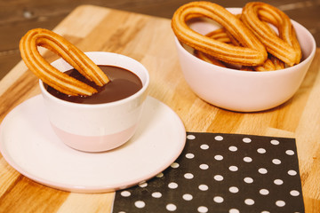 spanish fritters served on a wooden table with a cup of hot chocolate