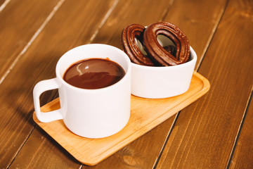 small spanish chocolate fritters served on a wooden table with a cup of hot chocolate