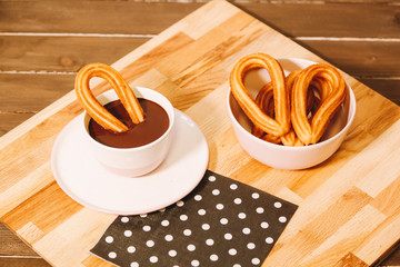 spanish fritters served on a wooden table with a cup of hot chocolate