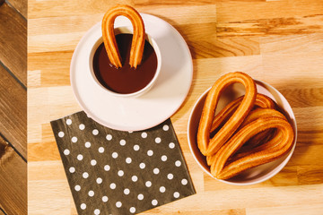 spanish fritters served on a wooden table with a cup of hot chocolate