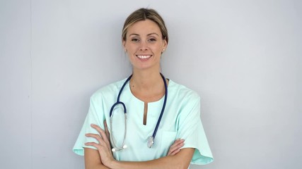 Attractive nurse smiling kindly at camera on grey background