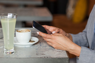 African woman texting a message at cafe. Close up