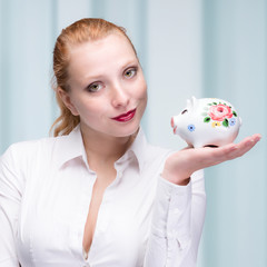 Fototapeta na wymiar young red haired woman with her piggy bank