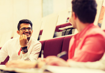 education, high school, university, learning and people concept - group of international students with notebooks writing in lecture hall