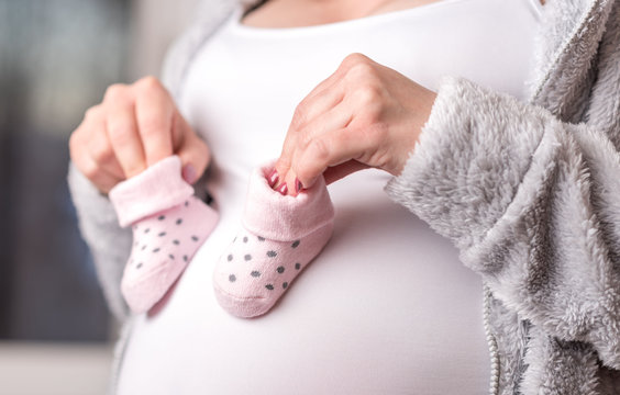 Pregnant Woman Holding Baby Shoes