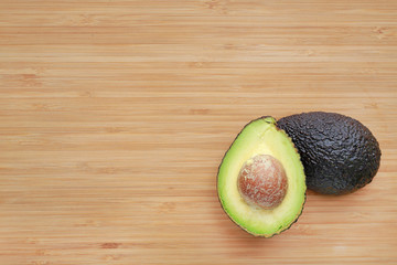 Avocado cut in half on wooden board background.