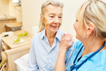 Pflegehilfe umarmt fürsorglich Seniorin