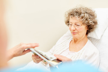 Senior Frau im Krankenbett beim Lesen