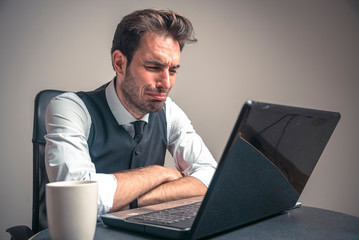 Crying sad business man receiving terrible news over his laptop, reading mail containing financial...