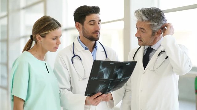 Doctors and nurse talking and walking with X-Ray in modern hospital