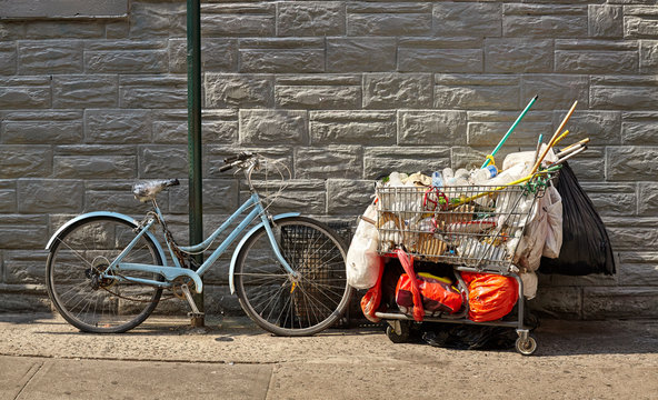 Old Bike And Shopping Cart Filled With Garbage On A Street Of New York City, USA.