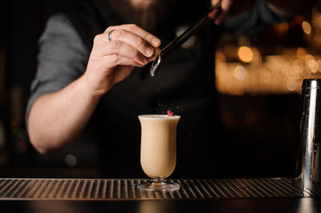 Fototapeta na wymiar Professional bartender adding to a delicious cocktail grated nutmeg