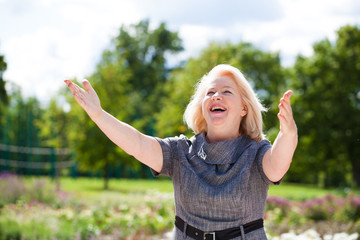 Fototapeta na wymiar Happy elderly woman on the background of summer park