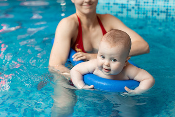 baby with mom learns to swim in the pool