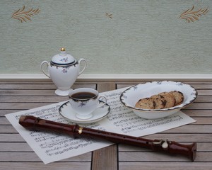 English teacup with saucer, sugar bowl and a cake bowl, fine bone china porcelain, and a block flute on a sheet of music