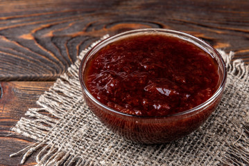 Strawberry jam on dark wooden background.