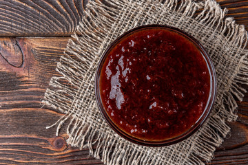 Strawberry jam on dark wooden background.