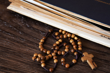 Wooden rosary beads on old books. Wooden background