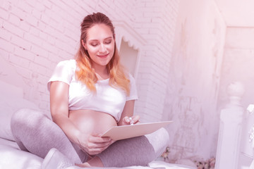 Young long-haired pregnant woman in a white t-shirt looking happy