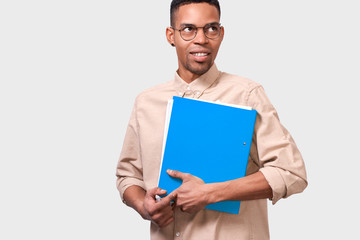 Confident male student in casual outfit with folder with papers and documents for exams with copy space for advertising. Young African American businessman holding folder with documents and statistics