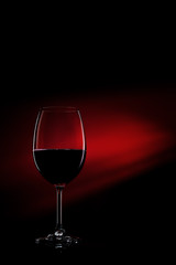 Glass of red wine on black to red gradient background. Concept studio shot.