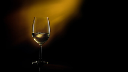 Conceptual shot of glass with white glass on a dark gradient black to yellow background.