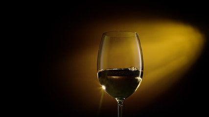 Glass of white wine on black to yellow background. Concept studio close-up shot.