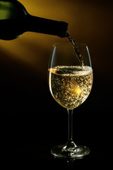 White wine being poured in a wine glass on a dark background. Studio close-up shot.