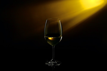 White wine in a glass on a gradient black to yellow background. Studio shot.