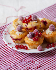 Delicious homemade raspberry cupcakes for a birthday party. Decorated with berries and almond, served on a red festive napkin. White plate. Daylight