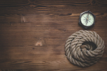 Fototapeta na wymiar Travel or adventure flat lay background with a copy space. Mooring rope and a compass on a wooden table.