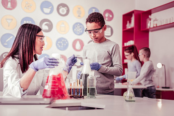 Curious African American schoolboy assisting his teacher