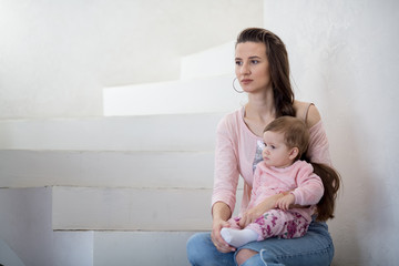 Mom holds her daughter in her arms. White background.